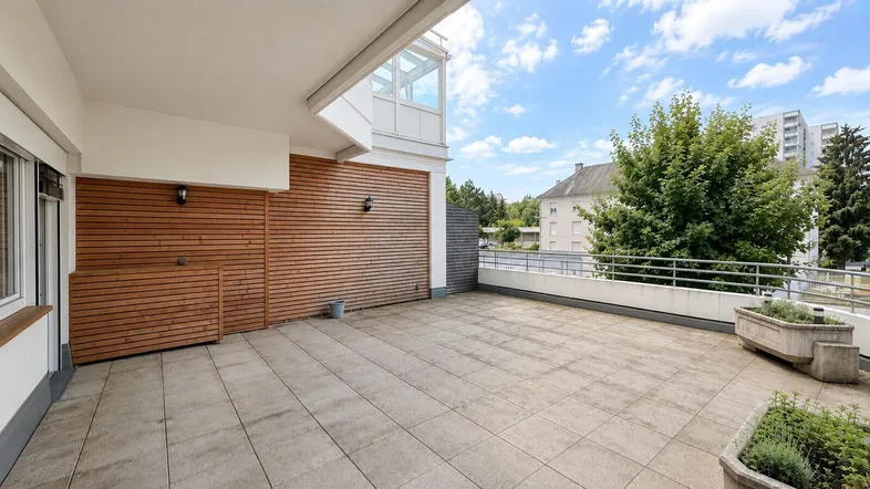 Weitläufige Terrasse mit Blick ins Grüne und auf die umliegende Wohnbebauung, perfekt für Erholung.