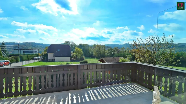 Geräumiger Balkon mit Holzbalkongeländer und weitem Blick über die grüne Landschaft.