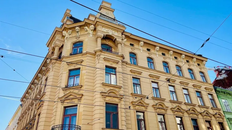 Eindrucksvolle Fassade eines historischen Eckgebäudes mit kunstvollen Verzierungen unter blauem Himmel.