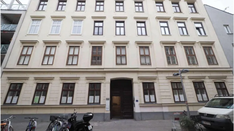 Historisches Mehrfamilienhaus mit klassischer Fassade und vielen Fenstern an einer Stadtstraße.
