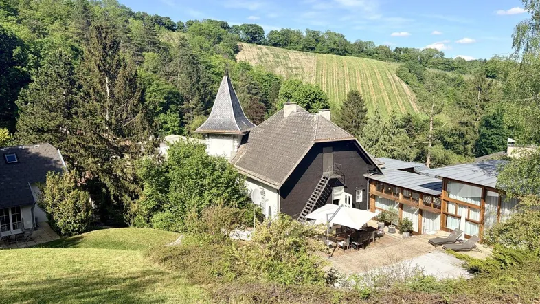 Weitläufige Außenansicht des Anwesens mit großer Terrasse, umgeben von grünen Hügeln und Weinbergen.
