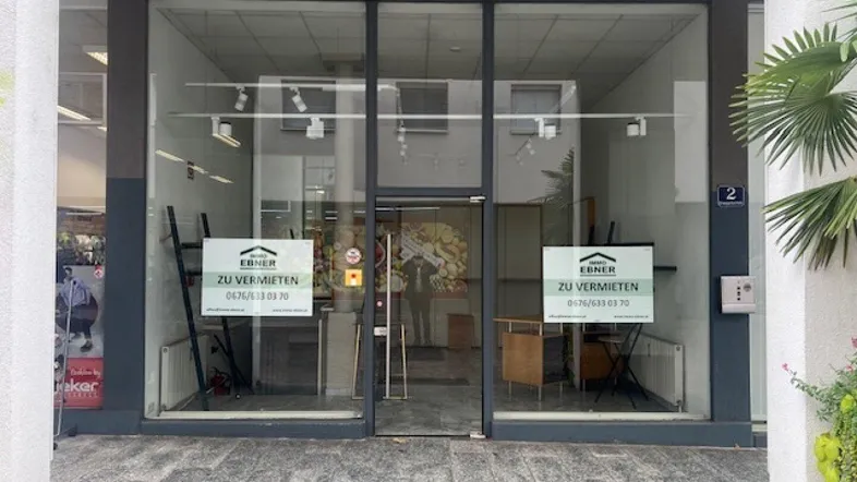 Eingangsbereich eines Ladenlokals mit großen Glasfenstern und 'Zu vermieten'-Schildern.