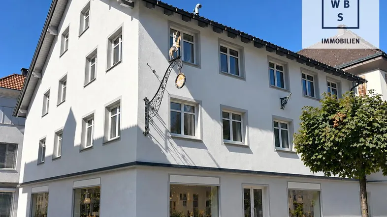 Modernes Gebäude mit weißer Fassade und vielen Fenstern in einer städtischen Umgebung.