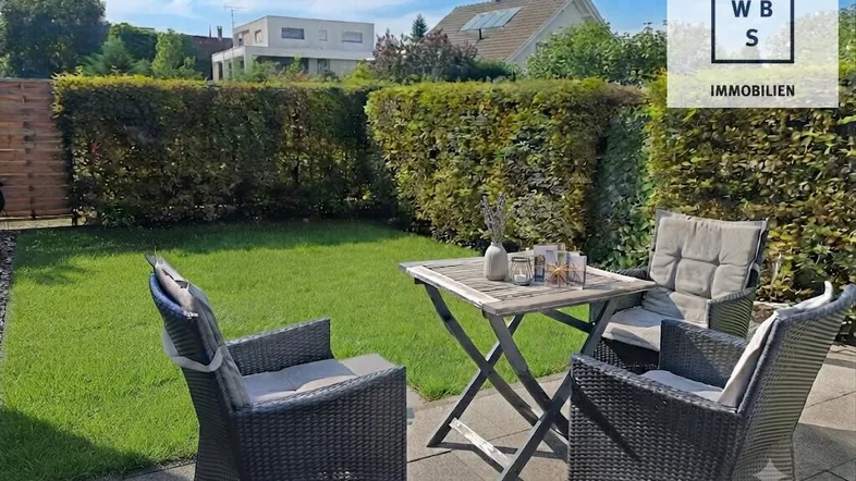 Gemütliche Terrasse mit Gartenmöbeln und Blick ins Grüne, umgeben von einer gepflegten Hecke.