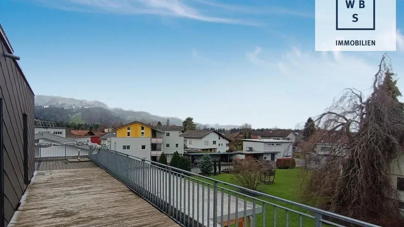 Geräumige Dachterrasse mit Holzboden und weitem Blick auf die umliegende Landschaft und Berge.