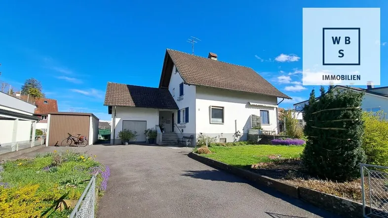 Freistehendes Einfamilienhaus mit Satteldach, Vorgarten und Zufahrt an einem sonnigen Tag.