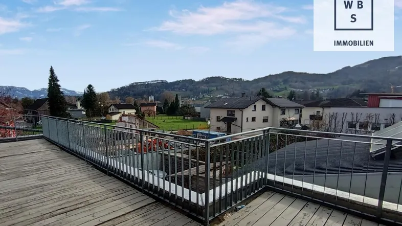Geräumige Dachterrasse mit Holzboden und weitem Blick über die umliegende Landschaft und Häuser.