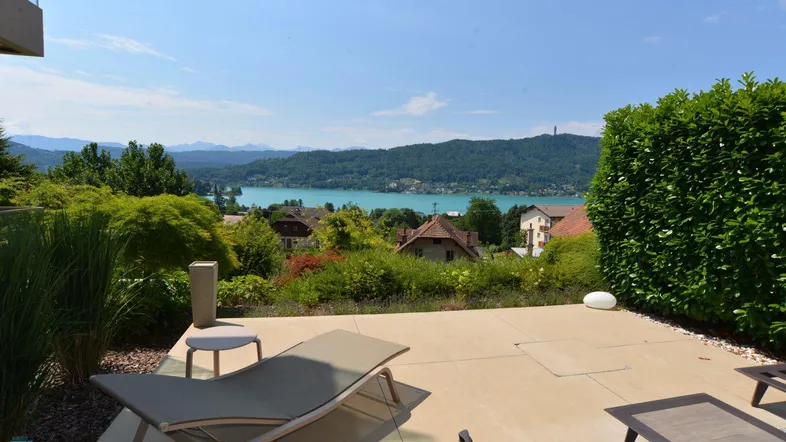 Große Sonnenterrasse mit bequemen Liegestühlen und einem atemberaubenden Blick auf den See und die Berge.