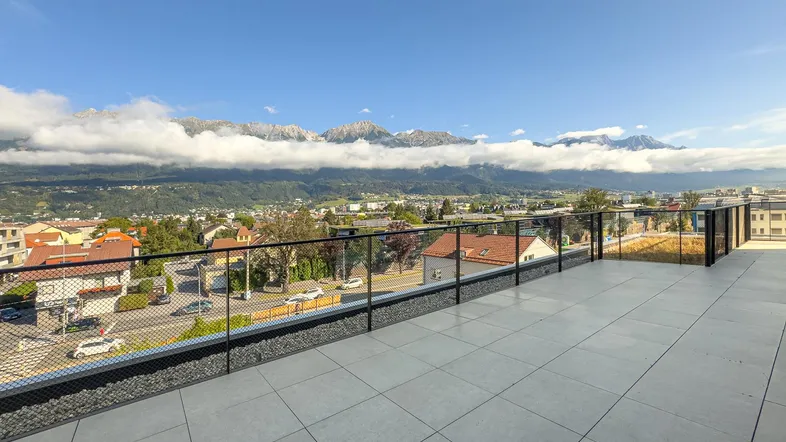 Große Dachterrasse mit Fliesenboden und weitem Blick auf die umliegende Berglandschaft.