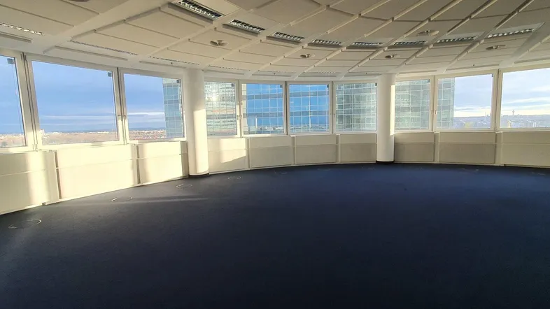 Großer, leerer Büroraum mit vielen Fenstern und weitem Blick über die Stadt.