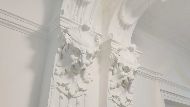 Detailaufnahme von aufwendigen Stuckverzierungen und Säulen in einem historischen Gebäude.