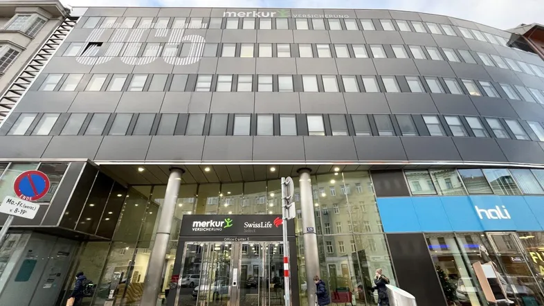 Modernes Bürogebäude mit Glasfassade und mehreren Etagen in städtischer Umgebung.