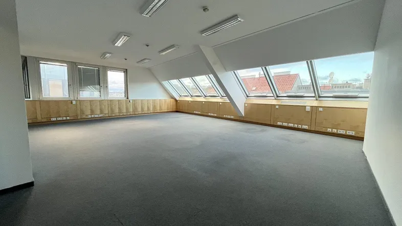 Geräumiges Büro im Dachgeschoss mit Teppichboden und vielen Fenstern, die viel Tageslicht hereinlassen.