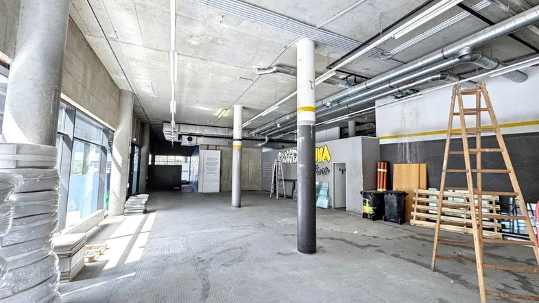 Großer, offener Gewerberaum mit Betonboden, hohen Decken und sichtbaren Installationen.