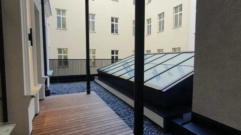 Eine moderne Terrasse mit Holzplankenboden und Kiesbett, die einen Blick auf den Innenhof bietet.
