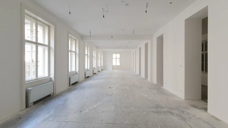 Großer, heller Büroraum mit vielen Fenstern und weiß gestrichenen Wänden, bereit für den Ausbau.