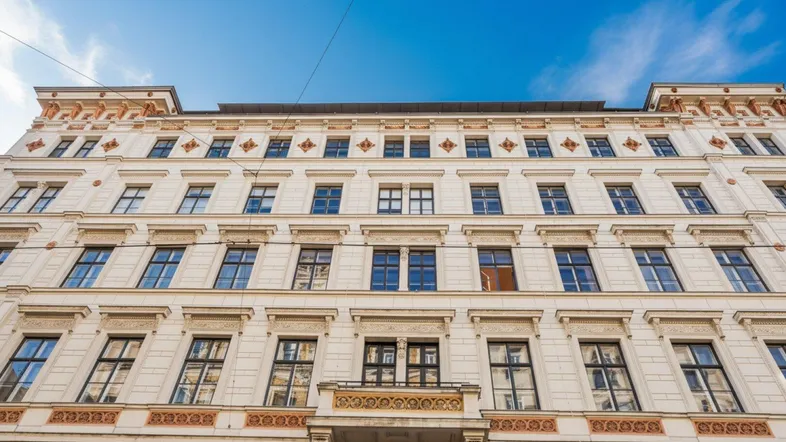 Historisches Gebäude mit reich verzierter Fassade, vielen Fenstern und einem kleinen Balkon unter blauem Himmel.