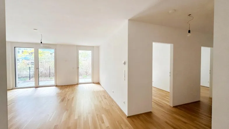 Helles und geräumiges Wohnzimmer mit Parkettboden und Zugang zu einer Terrasse oder Garten.