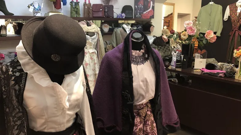 Innenansicht einer Boutique mit traditioneller Kleidung auf Schaufensterpuppen und dekorativen Elementen, die eine gehobene Atmosphäre schaffen.