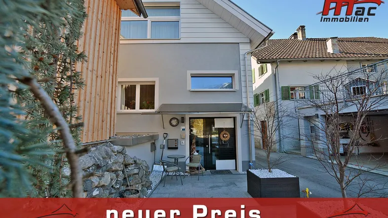 Vorderansicht des Hauses mit gepflastertem Eingangsbereich und kleiner Sitzgelegenheit.