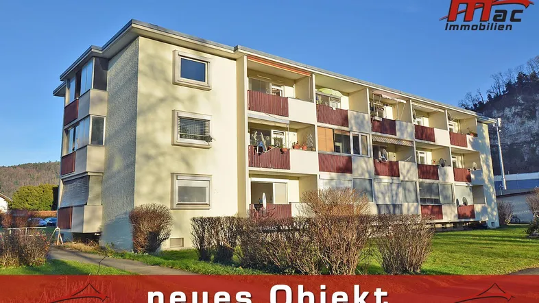 Mehrfamilienhaus mit mehreren Balkonen und gepflegter Grünfläche in sonniger Lage.