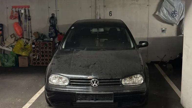 Dunkler Tiefgaragenstellplatz mit einem geparkten Auto und Lagerflächen im Hintergrund.