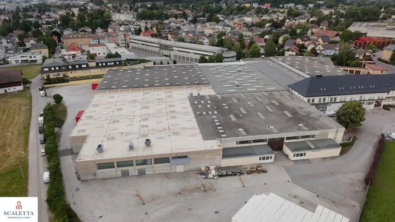 Luftaufnahme eines großen Industrie- und Gewerbekomplexes mit mehreren Hallen und umliegender Bebauung.