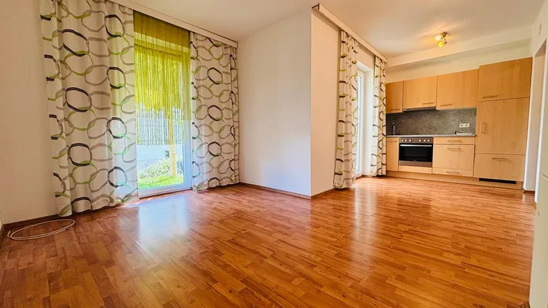 Heller offener Wohnbereich mit Holzboden und integrierter Küche, ideal für modernes Wohnen.