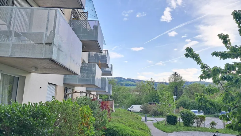 Moderne Wohnanlage mit Balkonen und grüner Umgebung unter einem weiten Himmel.