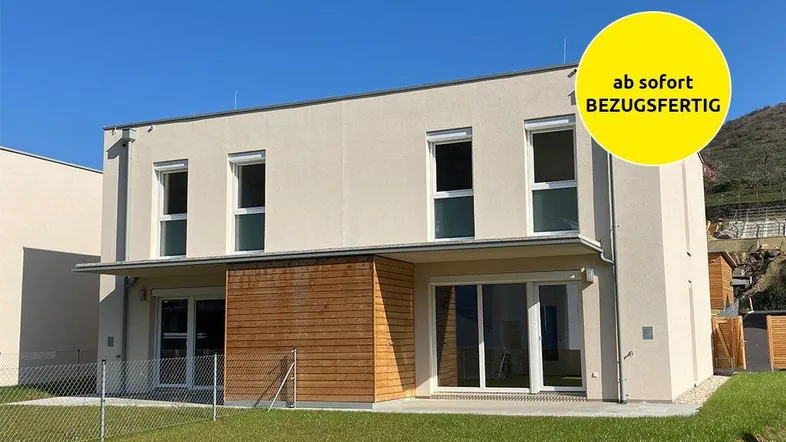 Modernes Reihenhaus mit heller Fassade, Holzverkleidung und kleinem Vorgarten, bezugsfertig.