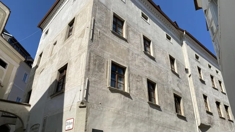 Historisches Gebäude mit aufwendiger Fassadenmalerei und traditioneller Architektur in einer Gasse.