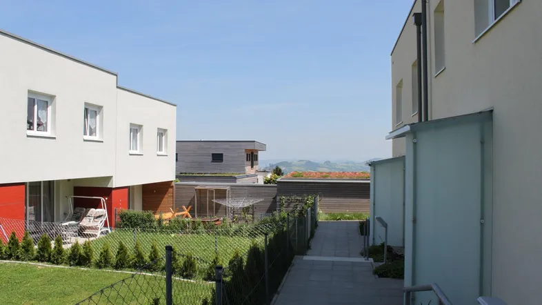 Moderne Wohngebäude mit privaten Gärten und einem weiten Blick auf die hügelige Landschaft.