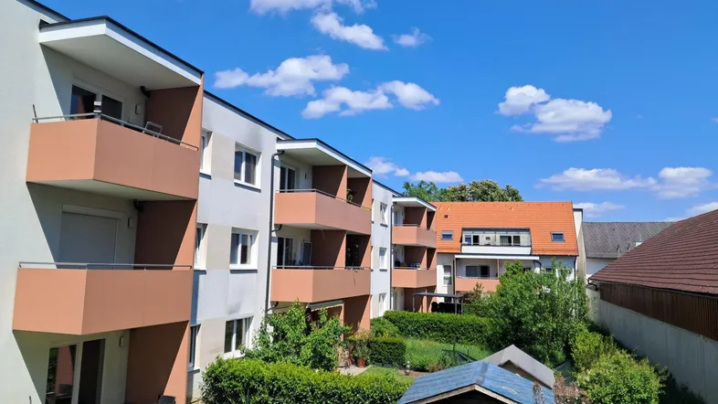 Mehrere moderne Apartmentgebäude mit Balkonen und einem gepflegten Gemeinschaftsgarten mit Gartenhaus.