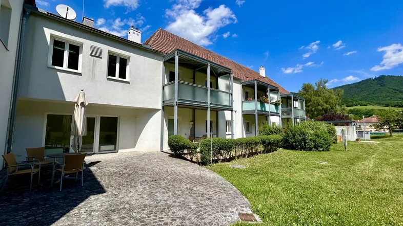 Große gepflasterte Terrasse mit Gartenmöbeln und Blick auf die umliegende Landschaft und Berge.