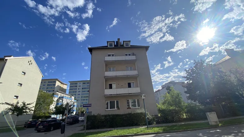 Mehrstöckiges Wohngebäude mit Balkonen unter blauem Himmel und Sonnenschein.