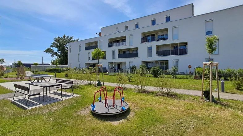 Moderne Wohnanlage mit Spielplatz, Sitzgelegenheiten und gepflegten Grünflächen für die Bewohner.