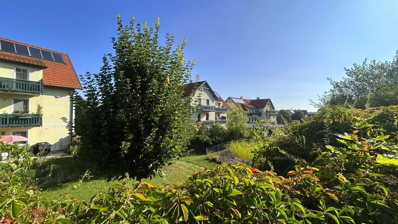 Blick auf die umliegende Wohnbebauung mit viel Grün und Bäumen unter blauem Himmel.