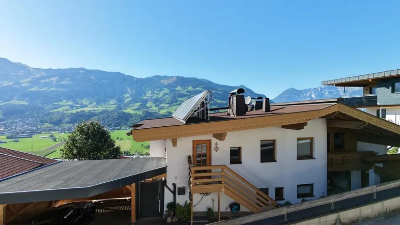 Traditionelles Haus mit Carport und Solaranlage, umgeben von einer malerischen Berglandschaft.