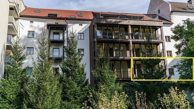 Ansicht eines modernen Wohngebäudes mit großen Glasfronten und umgebender Grünfläche.