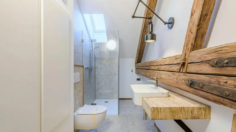 Modernes Badezimmer im Dachgeschoss mit begehbarer Dusche, Holzwaschtisch und sichtbaren Holzbalken.