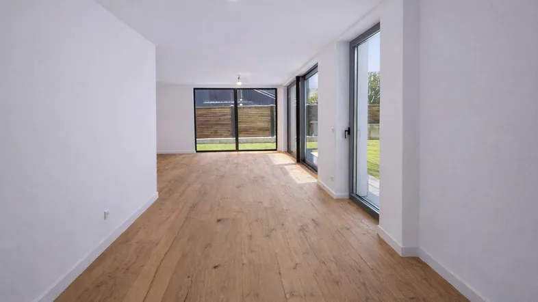 Geräumiger Wohnbereich mit Holzboden, viel Tageslicht und Zugang zum Garten.