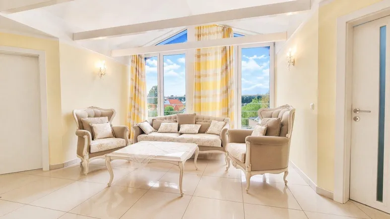Helles Wohnzimmer mit großen Fenstern, Fliesenboden und eleganten Möbeln, bietet einen weiten Ausblick.