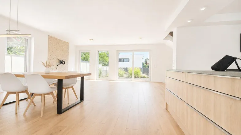 Heller, offener Wohn- und Essbereich mit Holzboden und Zugang zur Terrasse.