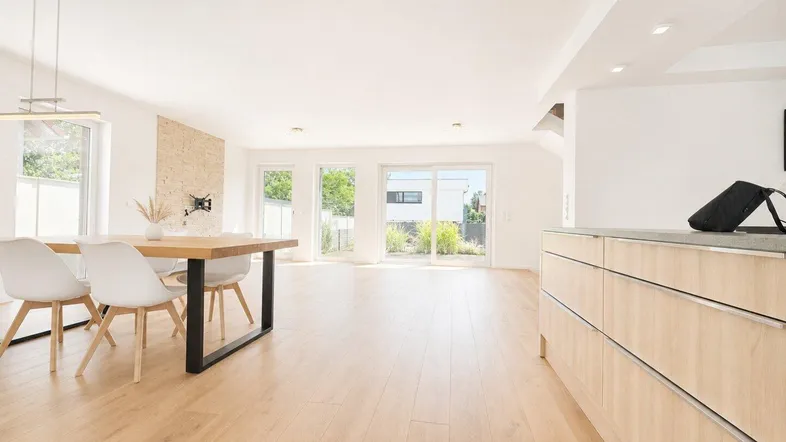 Heller, offener Wohn- und Essbereich mit Holzboden, großzügigen Fensterfronten und Zugang zum Garten.