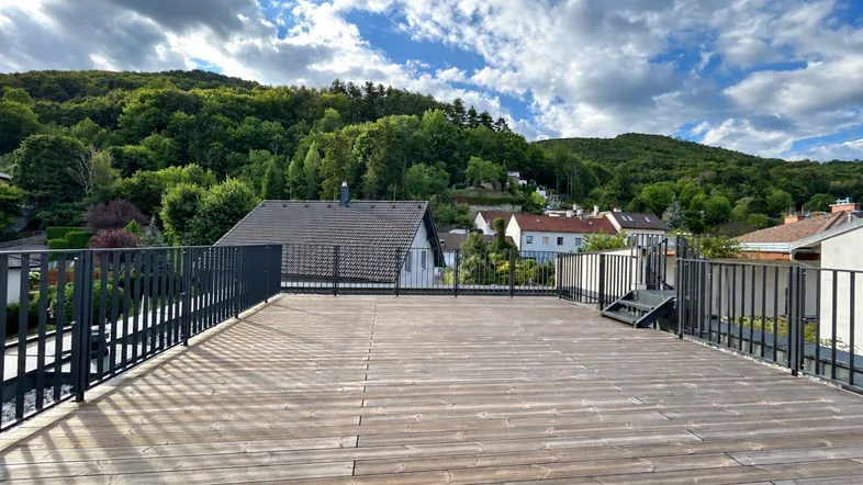 Geräumige Dachterrasse mit Holzboden und weitem Blick auf die umliegende grüne Landschaft.