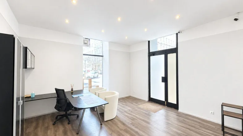 Helles Büro mit Laminatboden, modernen Möbeln und großen Fenstern zur Straße hin.