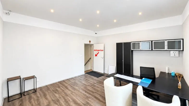 Helles Büro mit modernem Schreibtisch, weißen Stühlen und Zugang zum Kellergeschoss.