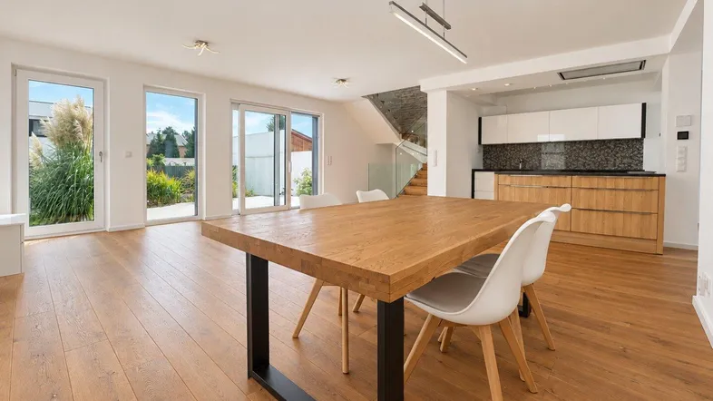 Essbereich mit Holztisch und modernen Stühlen, integriert in den offenen Wohn- und Küchenbereich.