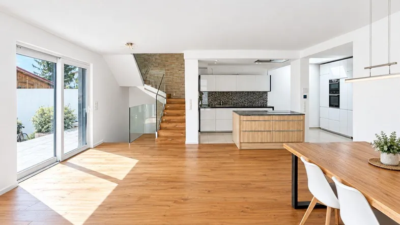 Heller offener Wohn- und Essbereich mit moderner Küche, Holzboden und Zugang zur Terrasse.