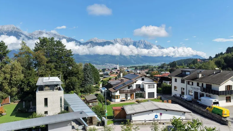 Panoramablick über eine ländliche Siedlung mit Bergen und blauem Himmel im Hintergrund.